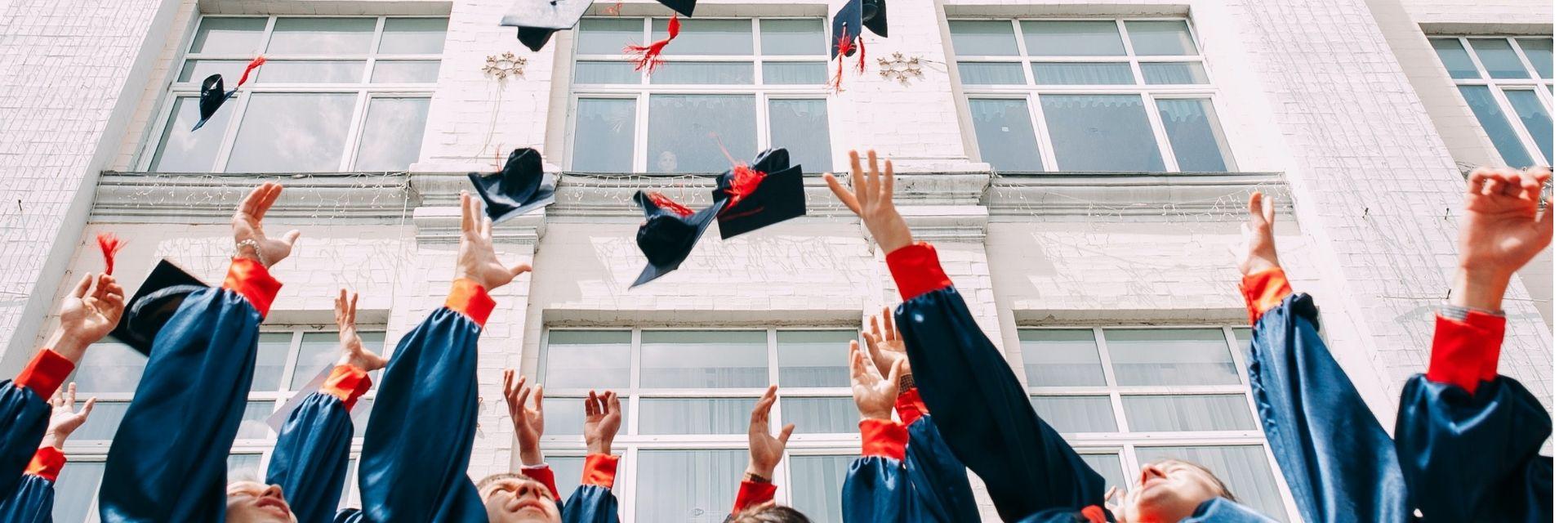 Graduation caps in air with student arms visible